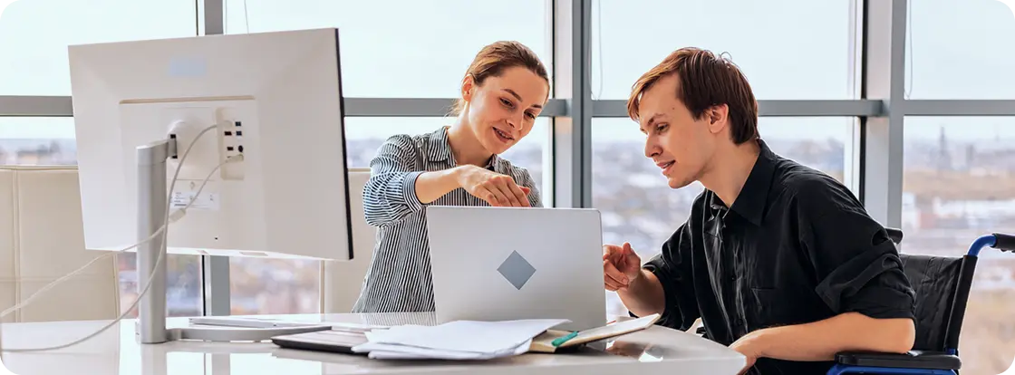 Two colleagues collaborating on a laptop in an office.