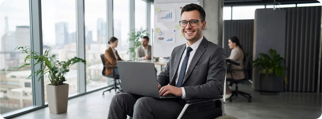 A businessman in a wheelchair using a laptop in a modern office